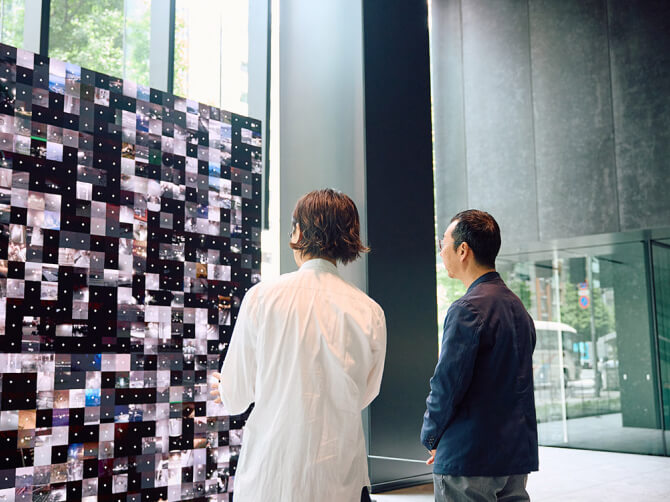 リアルタイムの風景映像が無数に並ぶダムタイプの作品「WINDOWS」に見入る山口周氏。