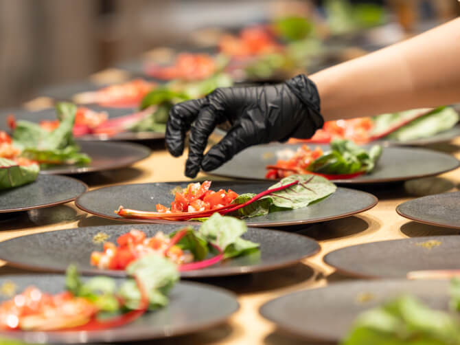 黒いプレートに野菜を盛り付けている様子。