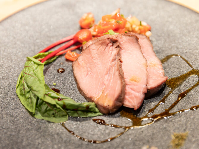 黒いプレートに盛り付けられたオーストラリア産牛肉の一皿。彩り野菜とソースが添えられている。