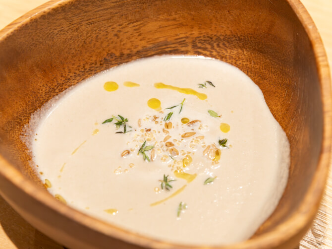 木製の器に入った穀物やハーブをあしらったスープ。