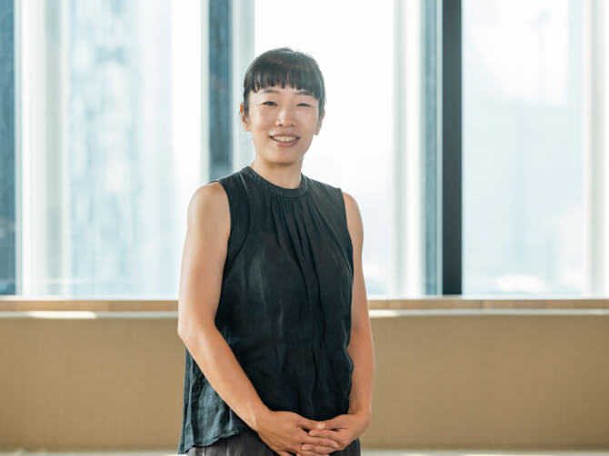 窓のある室内で、正面を向いて笑顔で立つ中山晴奈氏。