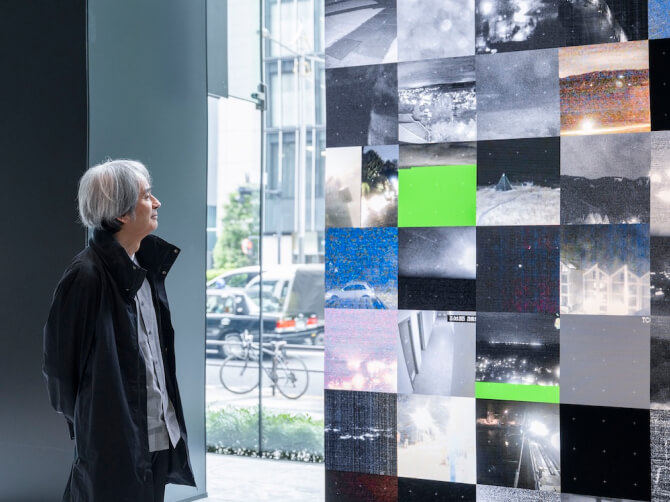 《WINDOWS》に格子状に映し出されているライブカメラの映像を穏やかな表情で見つめる高谷史郎氏。