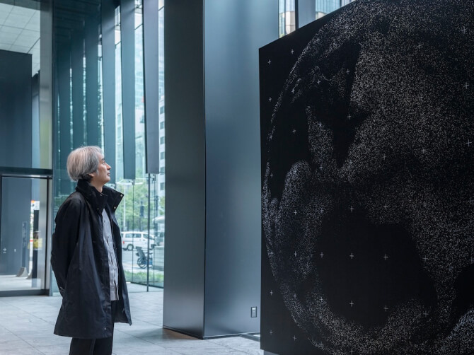 《WINDOWS》に地球儀のように映し出されている無数のライブカメラの映像を穏やかな表情で見つめる高谷史郎氏。