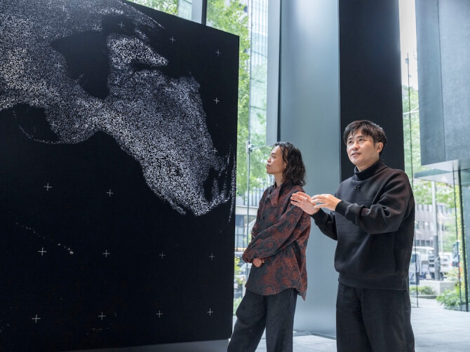 《WINDOWS》の前に立ち、作品のコンセプトについて身振りを交えて語る濱哲史氏と、穏やかな表情で見つめる古舘健氏。