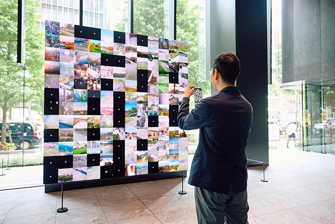ミュージアムタワー京橋のエントランスにある作品をスマートフォンで撮影する山口周氏。山口氏のインタビュー記事「人間の認知を揺さぶる、自然とアートの情報量」のサムネイル。