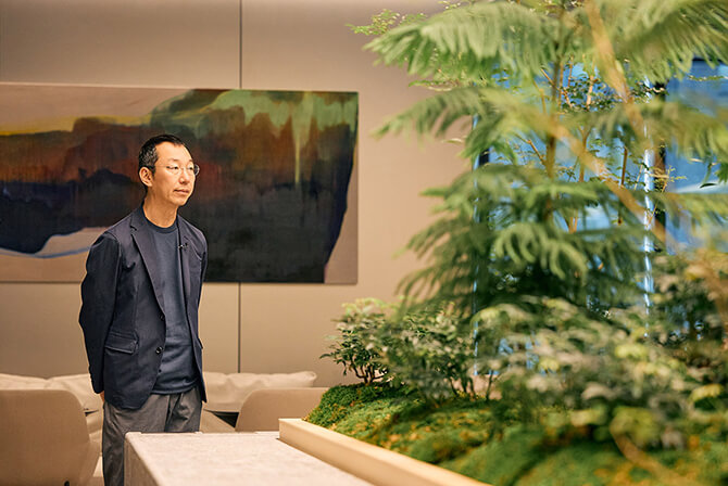 ミュージアムタワー京橋の3階オフィスラウンジにて、穏やかな光と植栽が調和する空間に佇む山口周氏。山口氏のインタビュー記事「知的生産の第一歩は、環境の機微を感じ取ること」のサムネイル。
