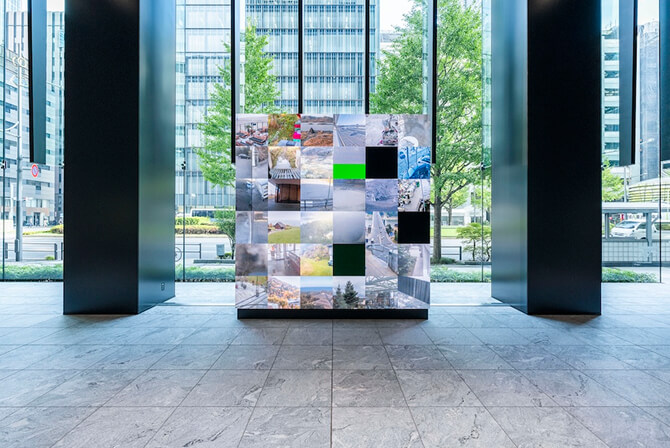 ミュージアムタワー京橋1階のエントランスに設置された《WINDOWS》。世界中のライブカメラの映像が格子状に映し出されている。ダムタイプのインタビュー記事「ネットワークが巡る地球の新たなリアリティ」のサムネイル。