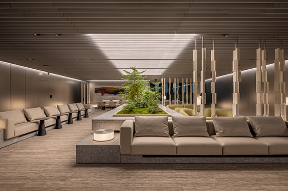 A view of the central axis of the lounge space, with the impressive gradation of louver lighting on the ceiling and plantings in the center.